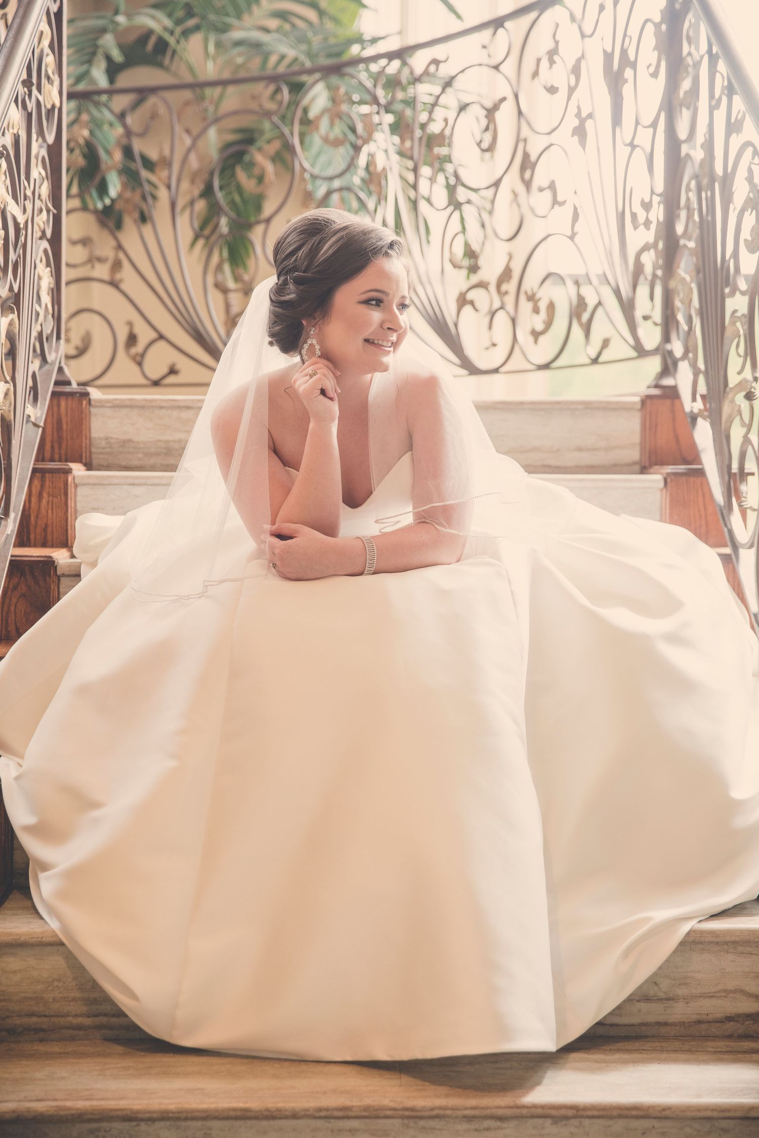 Romantic bridal portrait on vintage wooden floors with ornate iron railings and soft natural lighting.