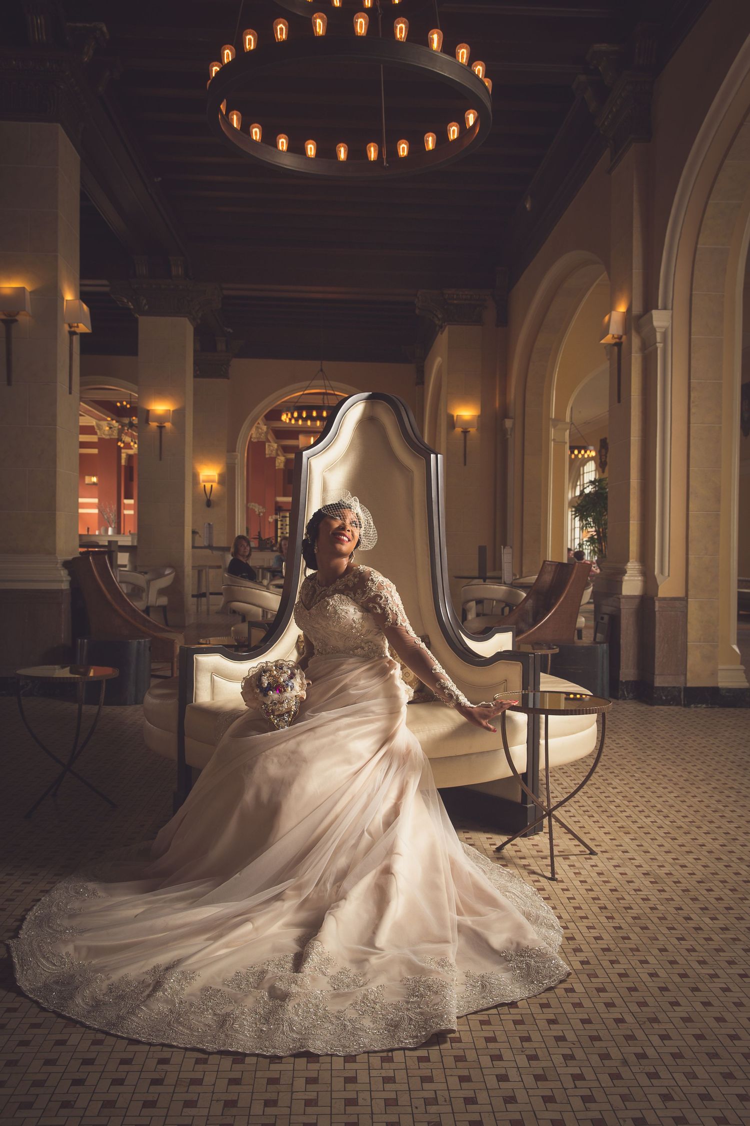 Dramatic wedding dress photo in a grand ballroom with ornate architectural details and circular lighting fixtures.
