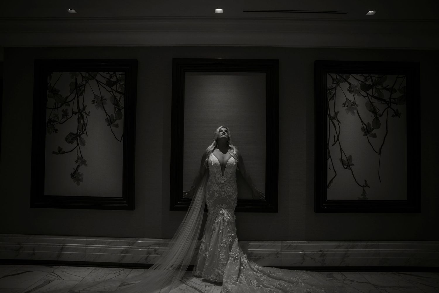 Artistic black and white wedding photography in a dark interior space with dramatic lighting.