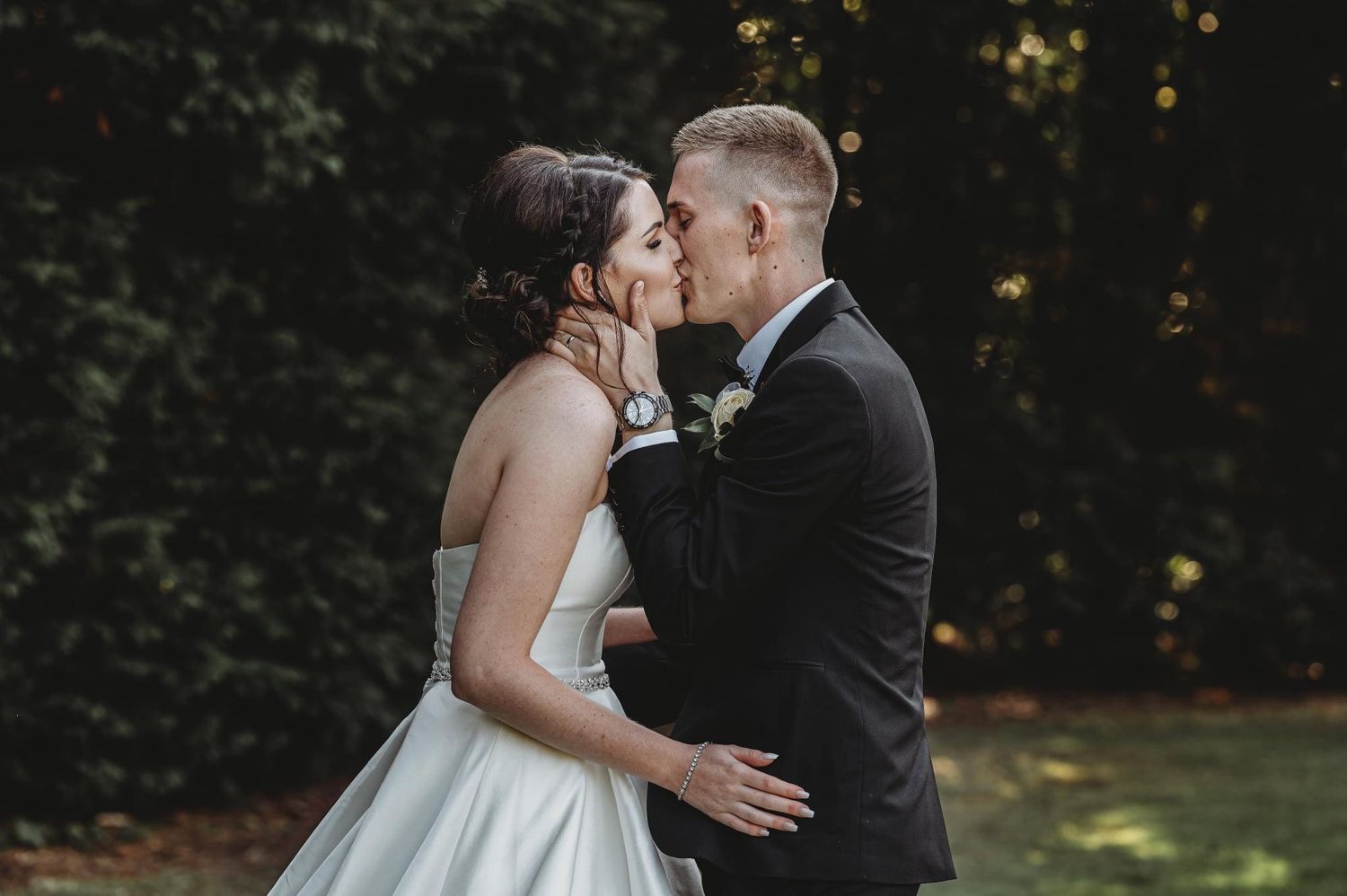 A tender wedding moment captured in a garden setting with soft natural lighting.