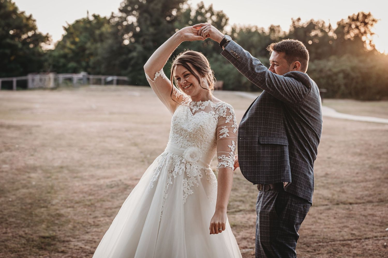 A couple dancing in an outdoor field during sunset.