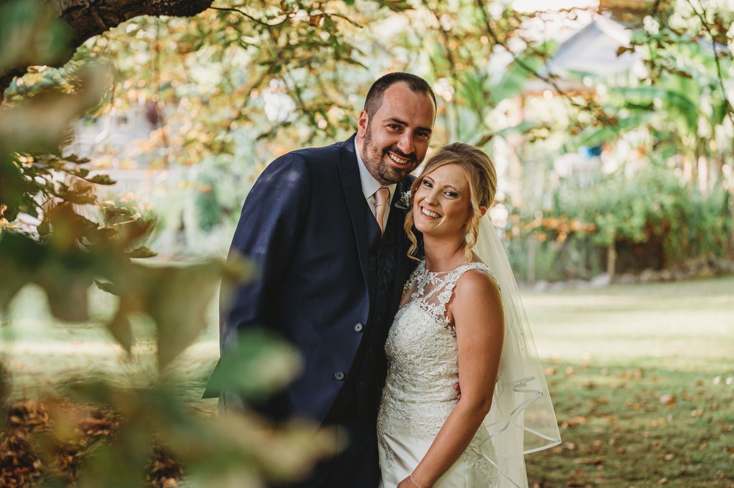 Romantic wedding portrait of couple sharing a tender moment in natural outdoor setting.