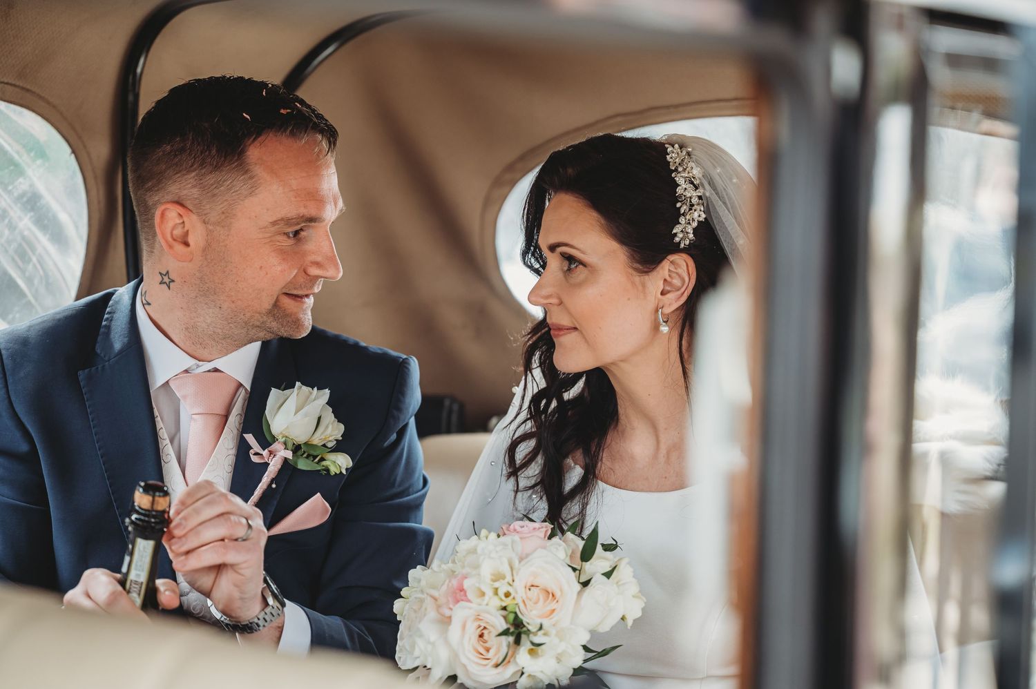 A wedding couple shares an intimate moment inside a vintage car.