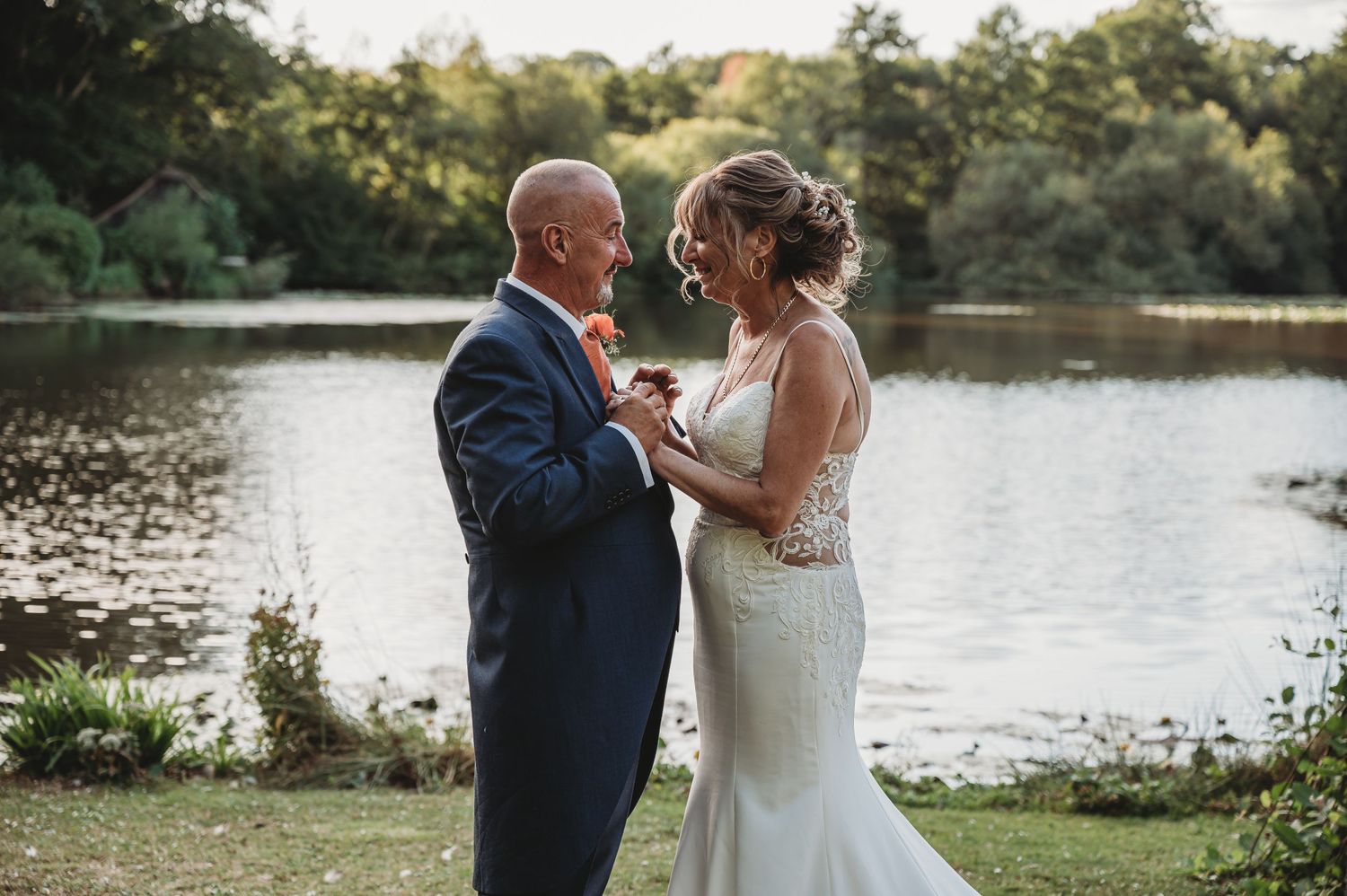 Romantic lakeside moment during golden hour at an outdoor wedding.