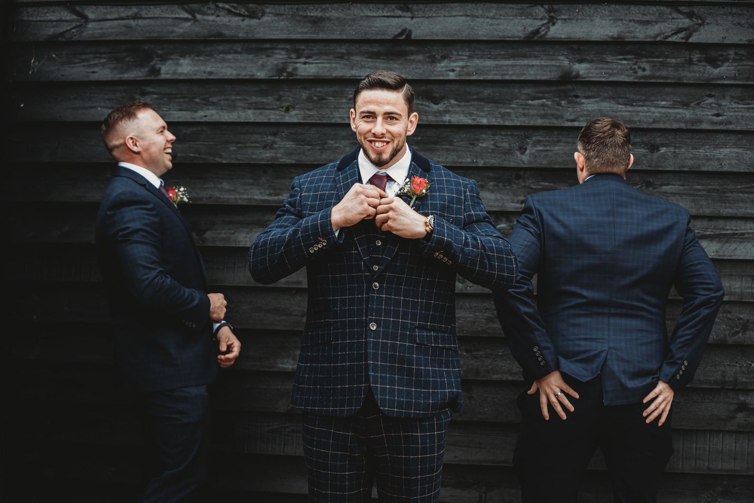 Creative groomsmen photo against dark wooden wall showing playful poses.
