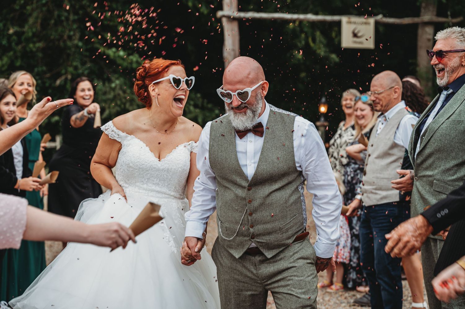 A wedding party celebration on a sunny day with guests throwing flower petals.