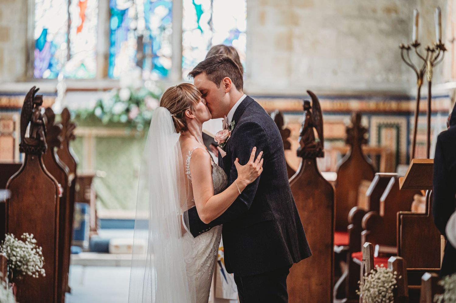 Couple shares their first dance in a historic church with stained glass windows.