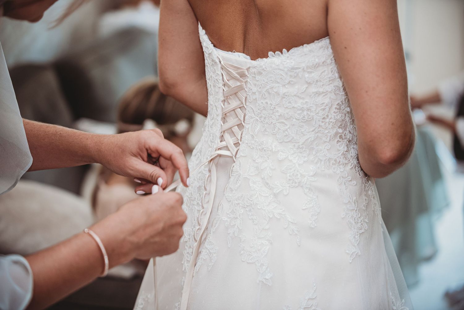 Close-up detail shot of lacing up white wedding dress corset back.