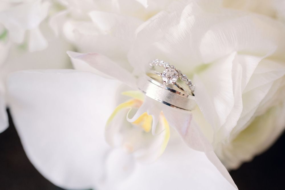 Diamond wedding rings nestled on a white flower petal.