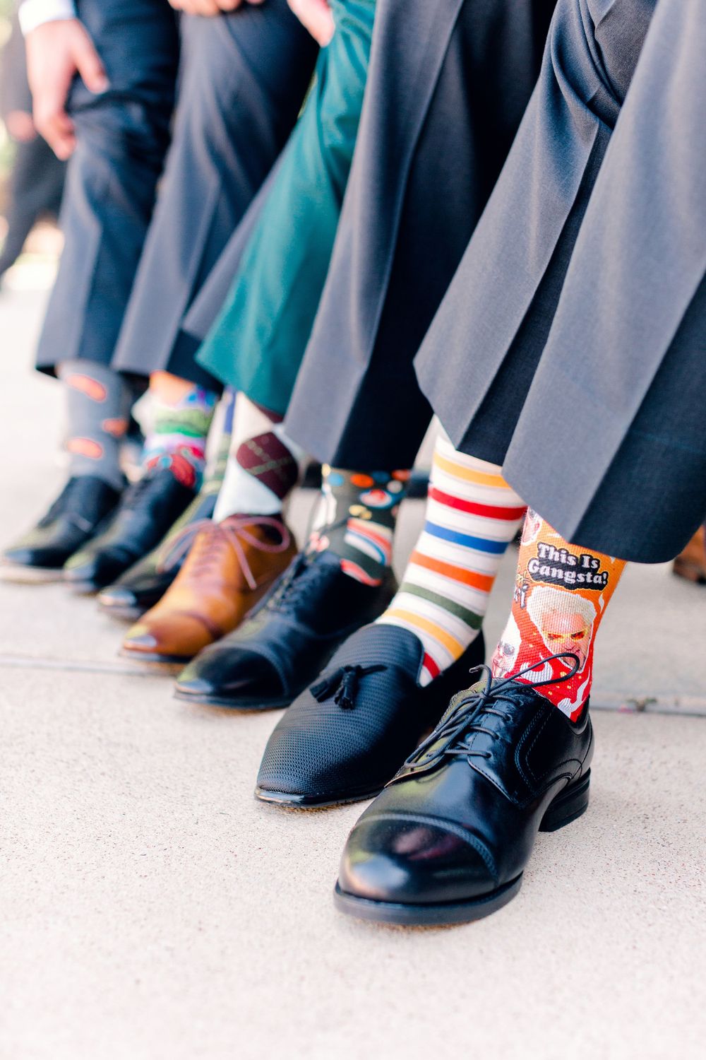 Fun groomsmen photo showing colorful patterned socks with dress shoes and suits.