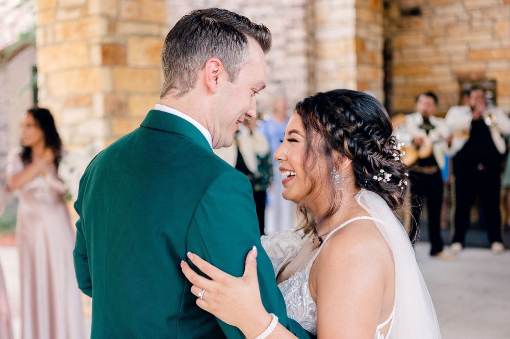 Candid moment of joy and laughter shared during wedding celebrations against stone architecture.