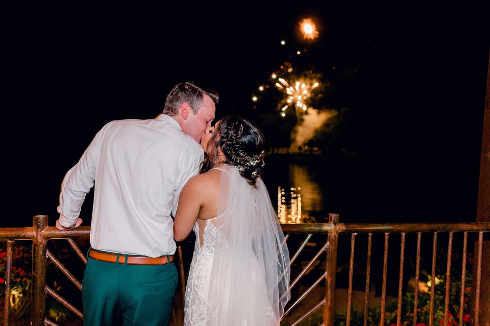 A couple shares a romantic moment on a terrace with sparklers glowing in the night sky.