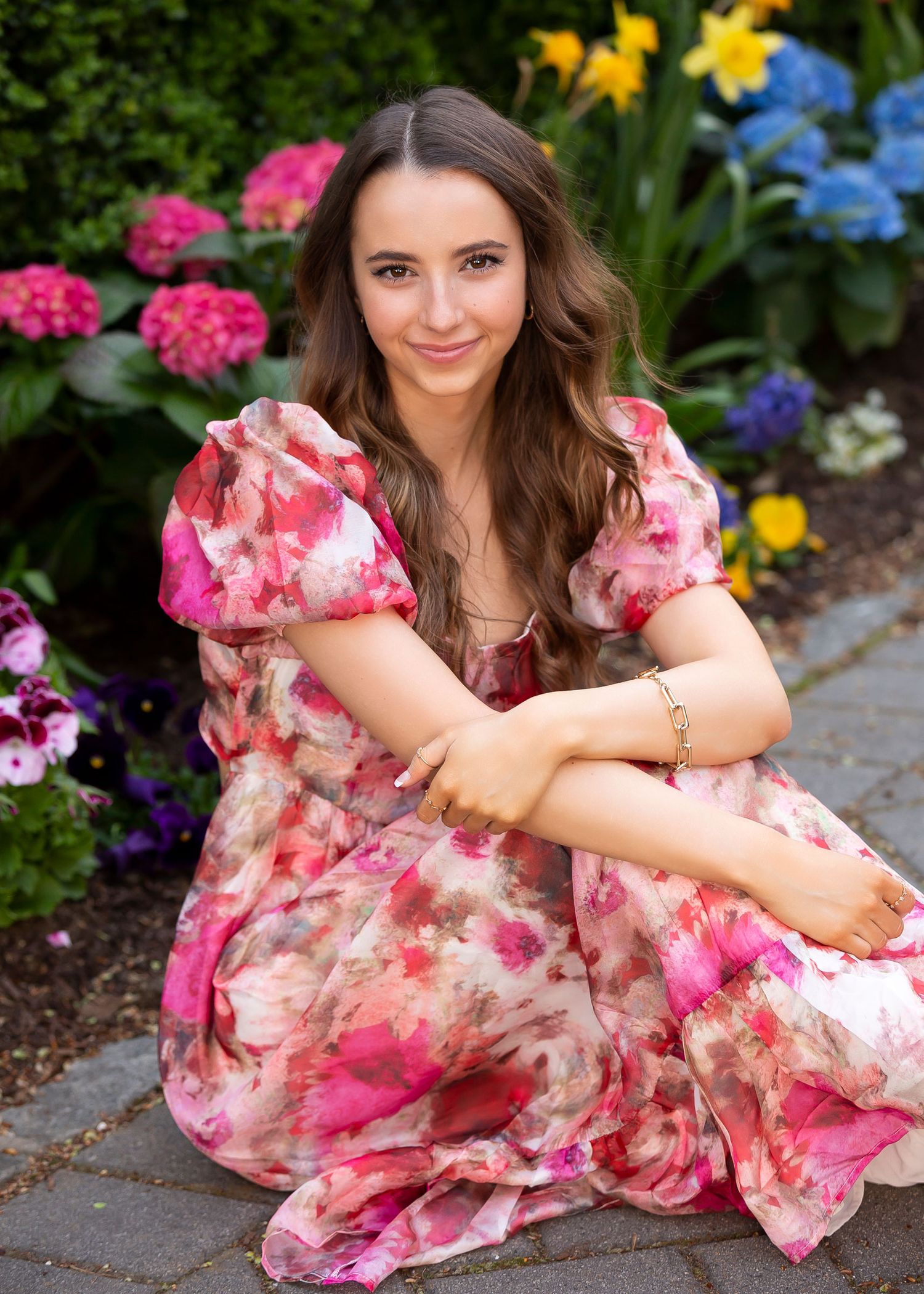 Garden portrait in pink floral dress surrounded by colorful summer blooms.
