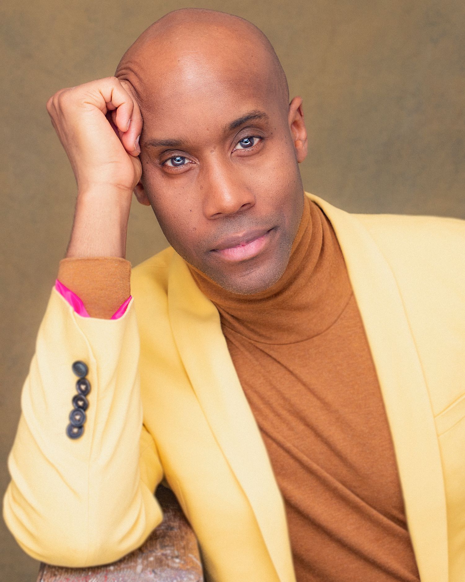 Professional headshot featuring someone in a yellow blazer and brown turtleneck.