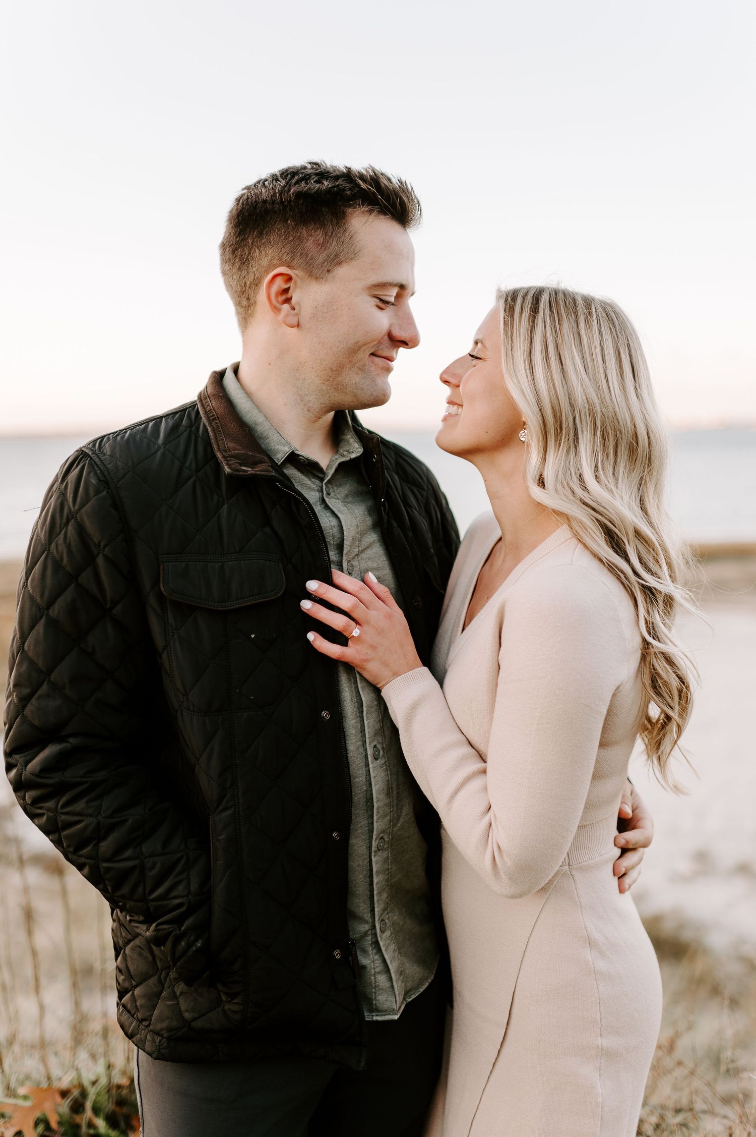 Intimate engagement photo of couple embracing outdoors in casual attire.