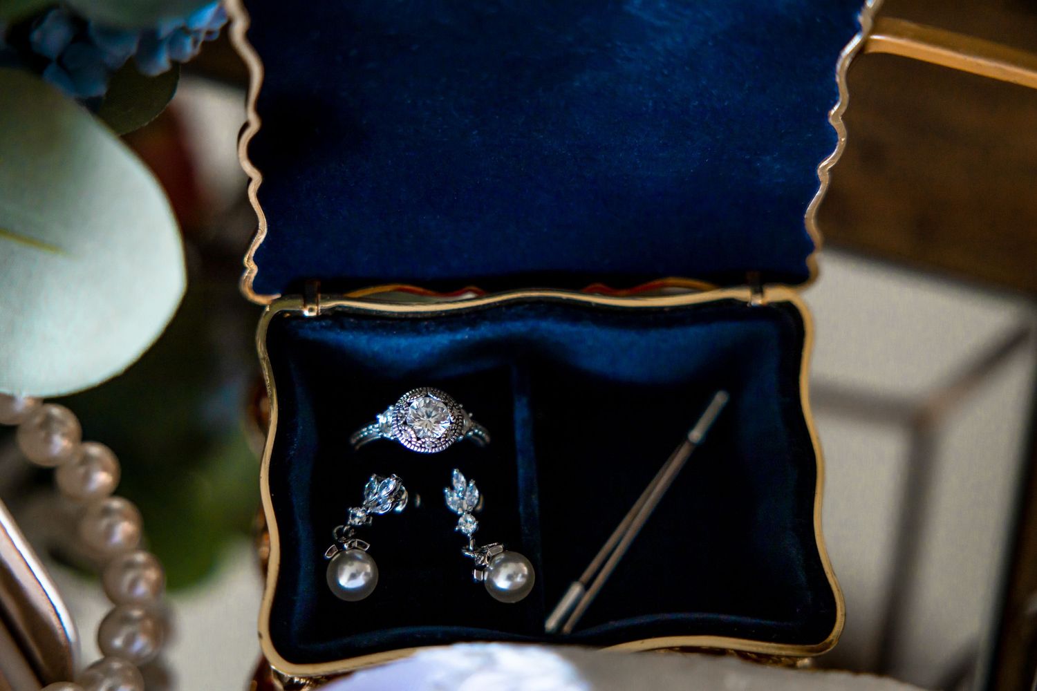 Diamond halo engagement ring and earrings displayed in a velvet jewelry box.