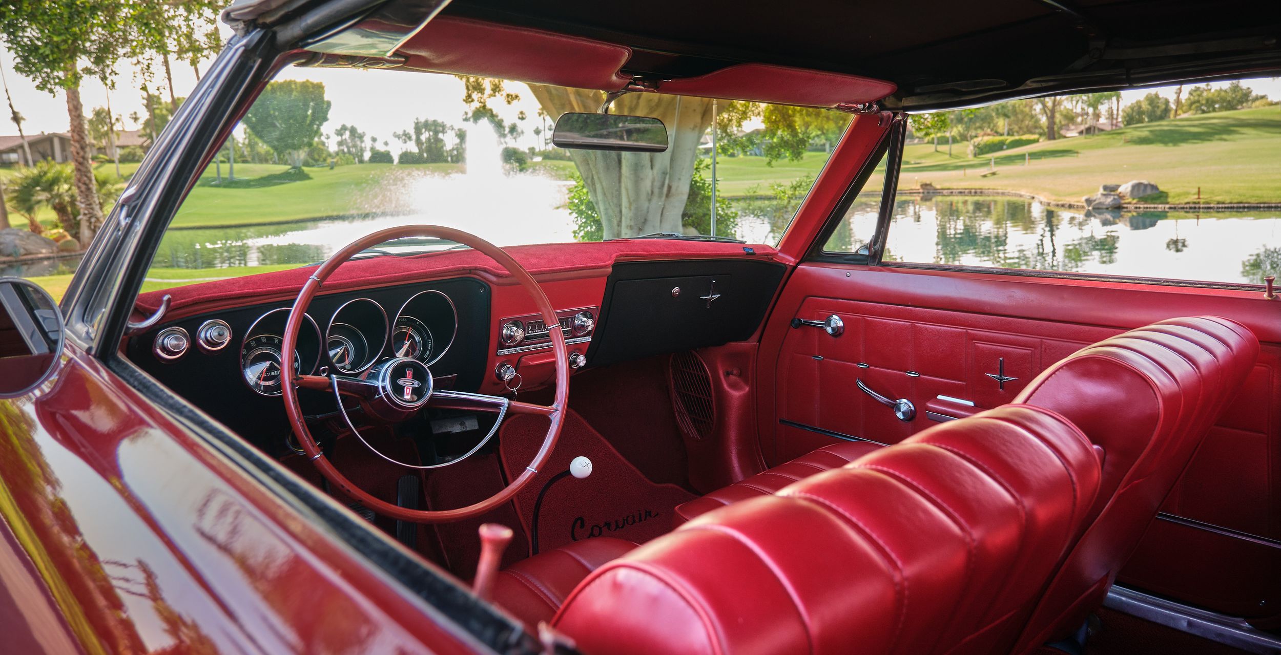 Classic car interior featuring bright red leather upholstery and vintage steering wheel.