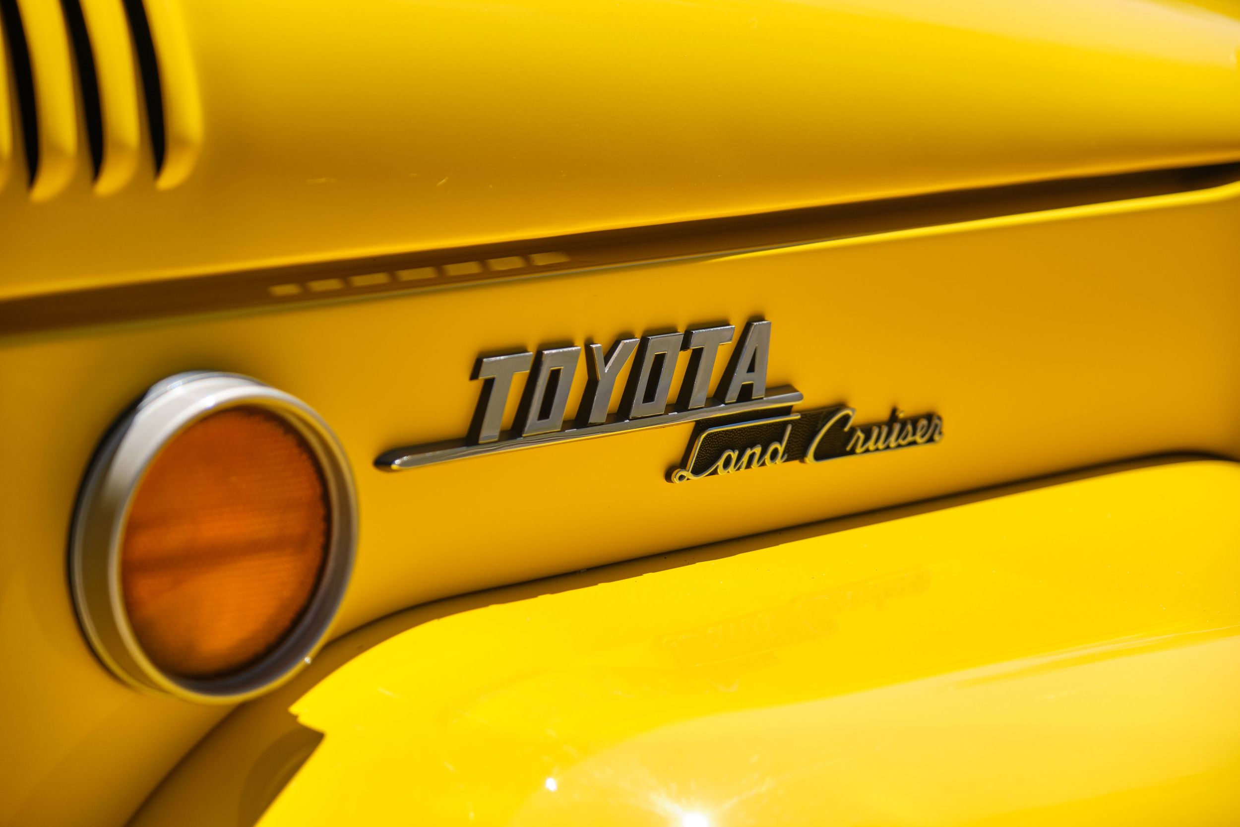 Close-up detail of yellow Toyota Land Cruiser badge on vehicle exterior.