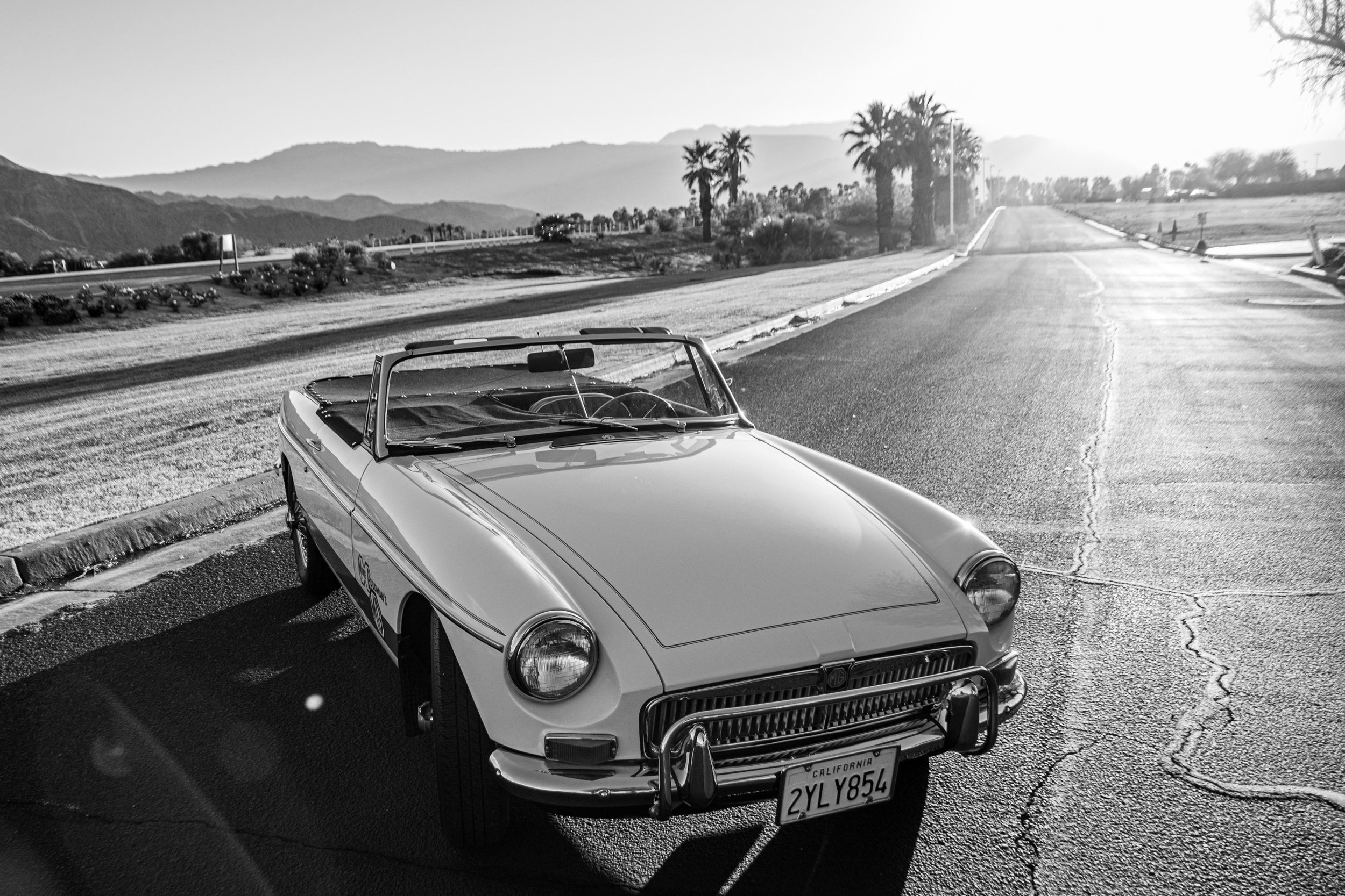 Vintage convertible photographed in black and white on scenic mountain road.
