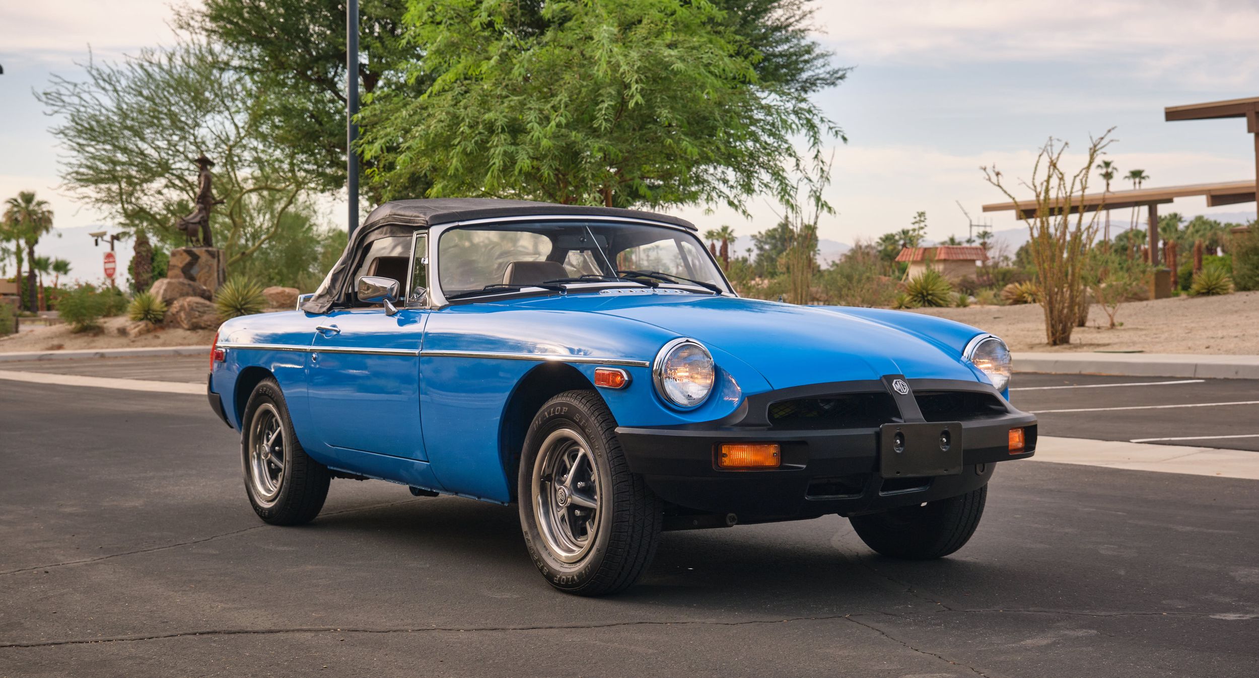 Bright blue MGB GT classic sports car parked on suburban street.