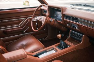 Brown leather interior of vintage car showing dashboard and manual transmission.