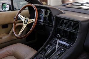Tan leather interior of classic Ferrari showing wooden steering wheel and instrument cluster.