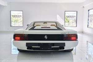 Rear view of white Ferrari Testarossa in clean modern showroom.