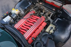 Red engine bay of a sports car showing detailed V12 engine components.