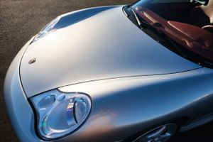 Close-up of silver Porsche headlight detail against metallic paint.