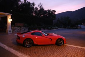 Red Dodge Viper parked at dusk with mountains in the background.