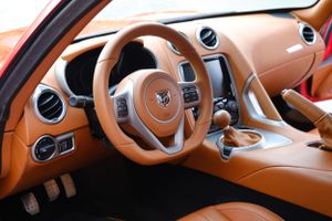 Luxury car interior featuring tan leather dashboard and modern circular air vents.