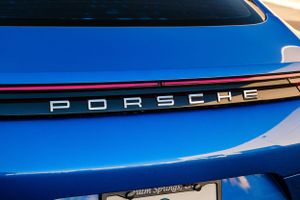 Close-up detail of blue Porsche vehicle with Porsche lettering on the rear deck.