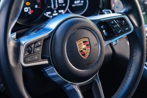 Modern Porsche steering wheel interior showing the iconic Porsche crest emblem.