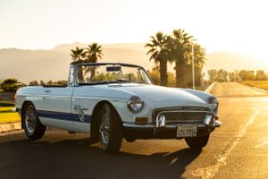 Classic white convertible sports car at sunset with palm trees in background.