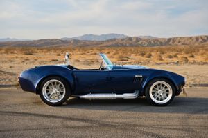 Classic blue Shelby Cobra roadster photographed in a desert landscape.
