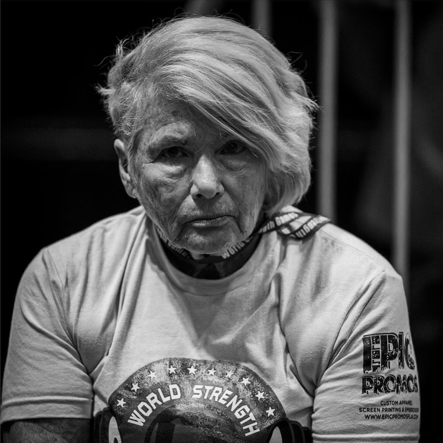 Black and white portrait of a powerlifter wearing a World's Strongest t-shirt.