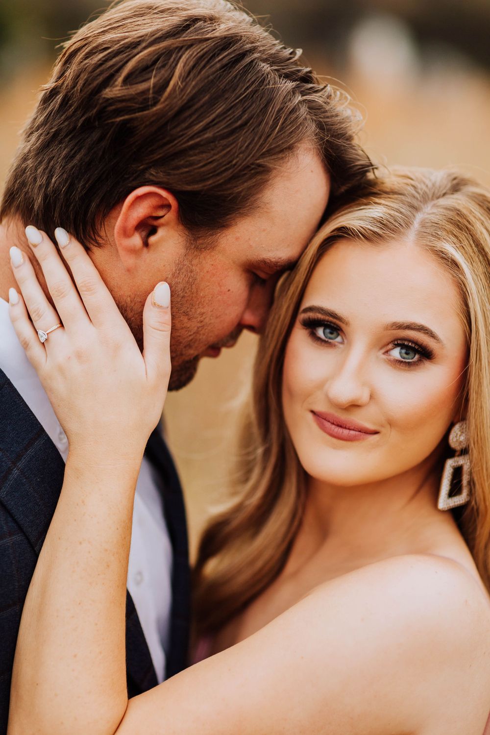 Intimate close-up of a blonde woman with blue eyes and diamond ring during an engagement photo session.