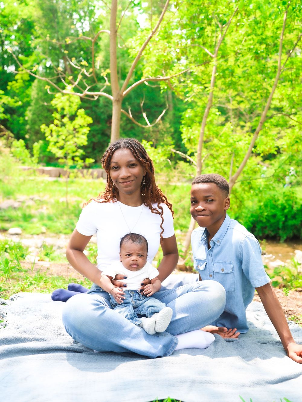 Family relaxing on picnic blanket in lush green garden setting.