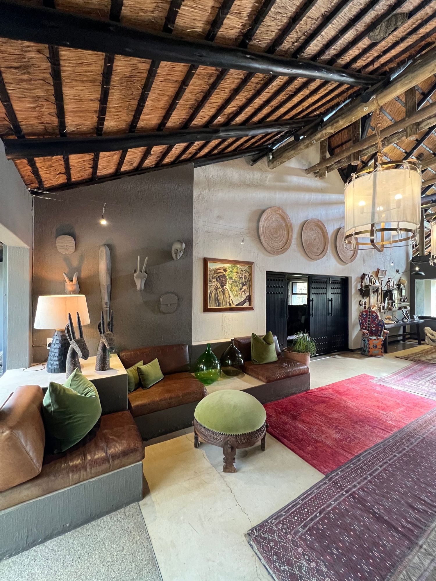 Lodge lounge area featuring rustic wooden ceiling, plush seating, and traditional African decor elements.