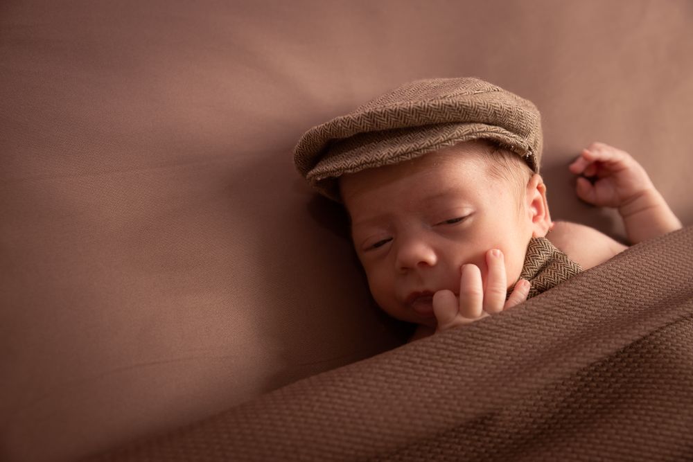 sleeping baby in brown blankets and hat and bowtie
