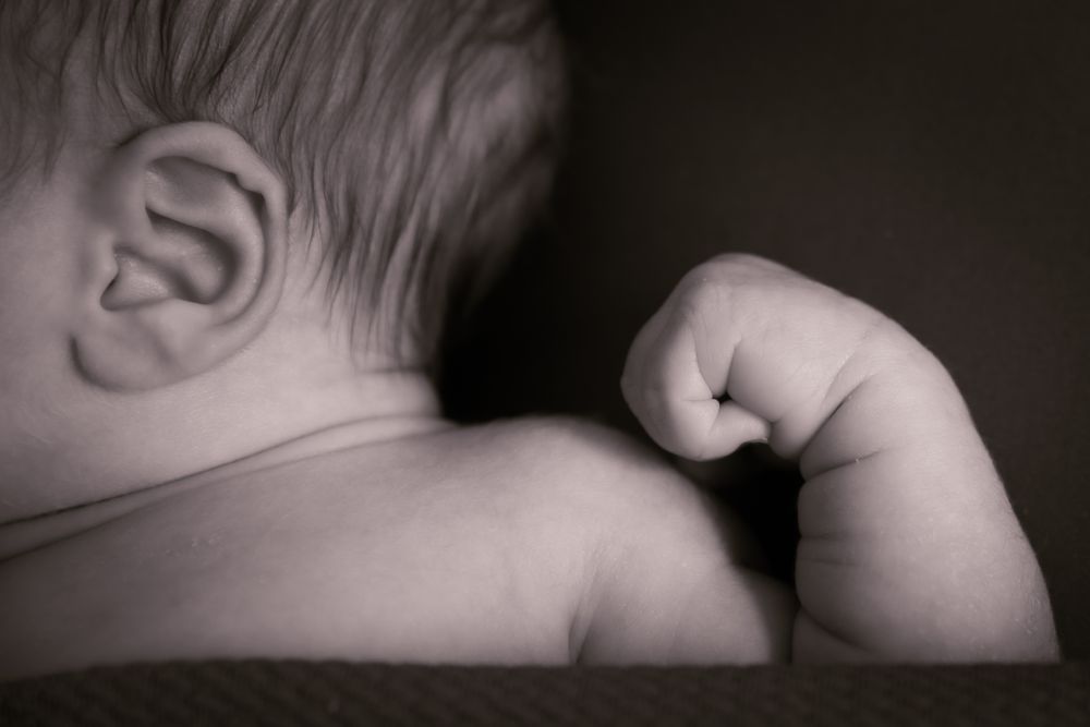 black and white photo of baby hand and ear