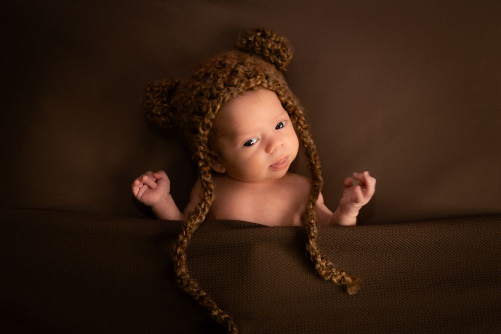 Baby dressed as teddy bear tucked in bed