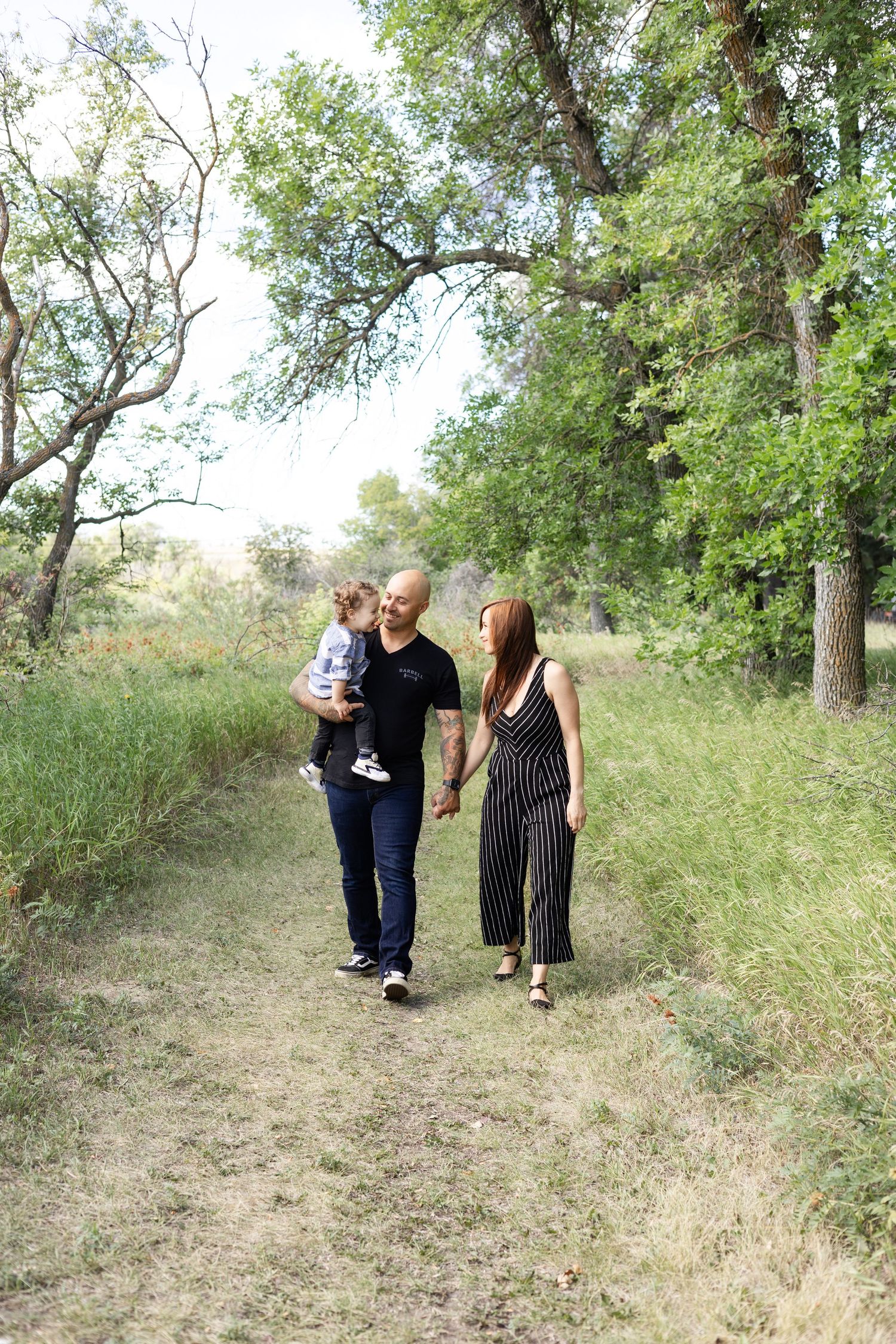 Family walking together on nature trail through wooded area.