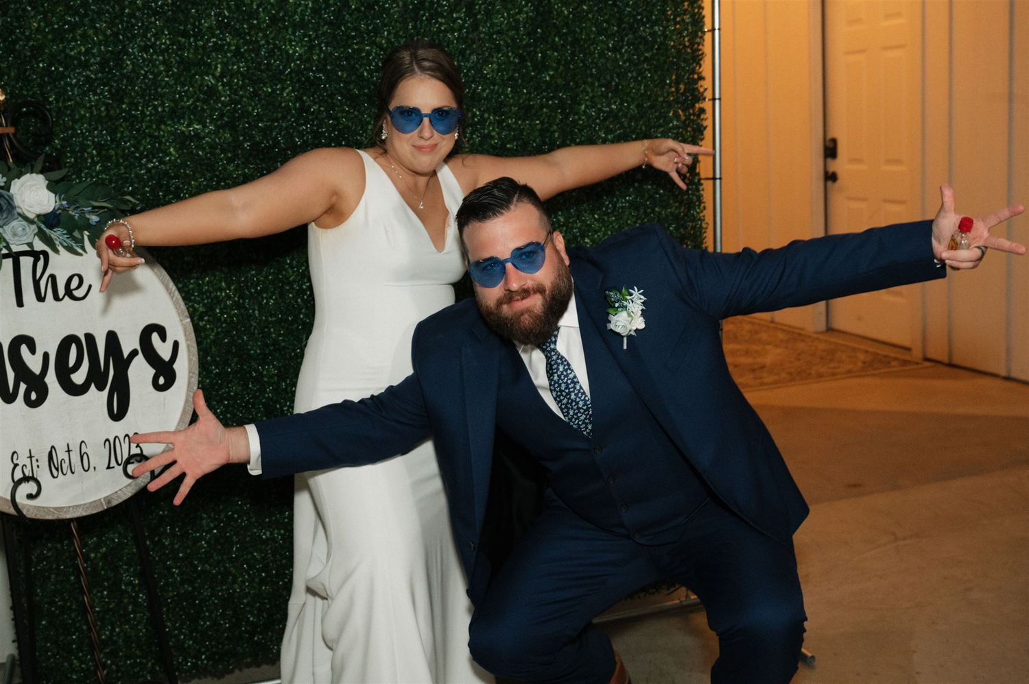 A fun pose with sunglasses at a wedding reception with a decorative backdrop.