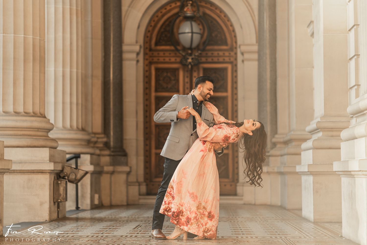 Romantic dance pose between pillars of a grand historic building.