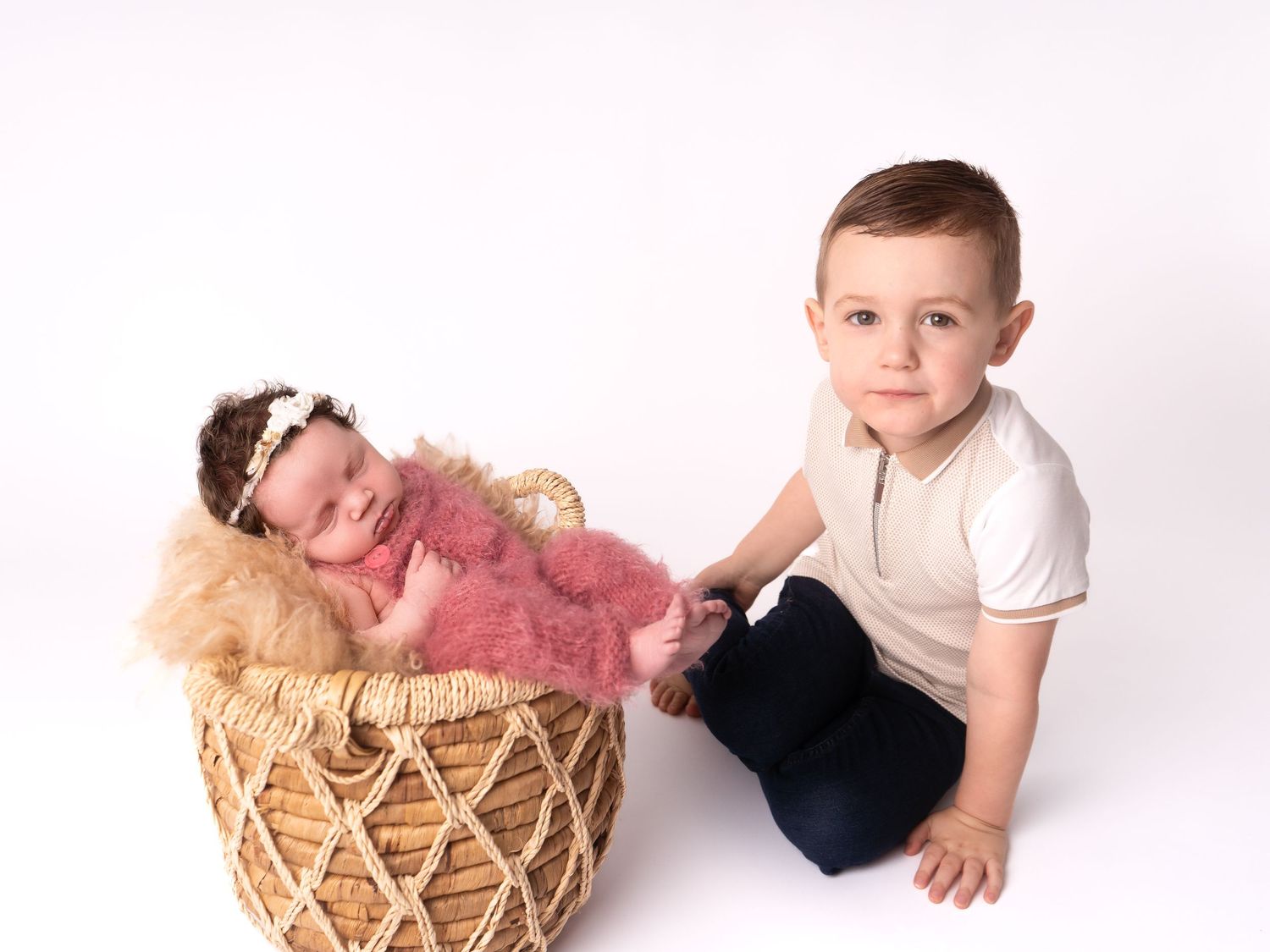 Sibling photo of boy and newborn baby girl with pink fluffy outfit and white headband taken by heather katie photography