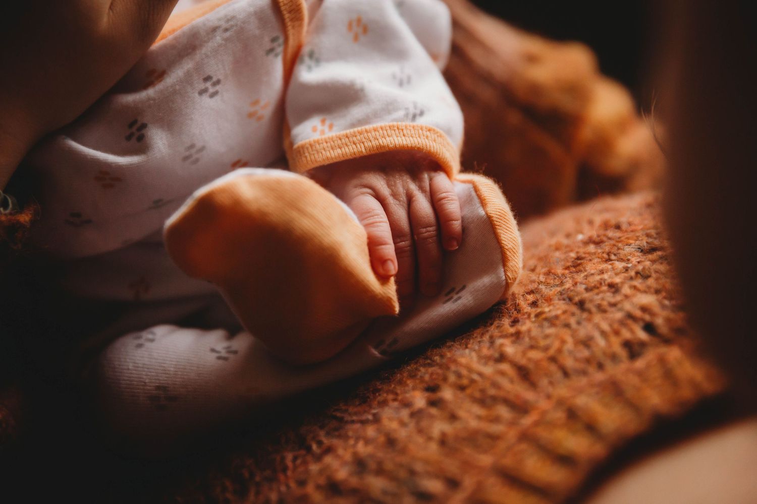 Close-up detail of baby's tiny feet on brown knit blanket.