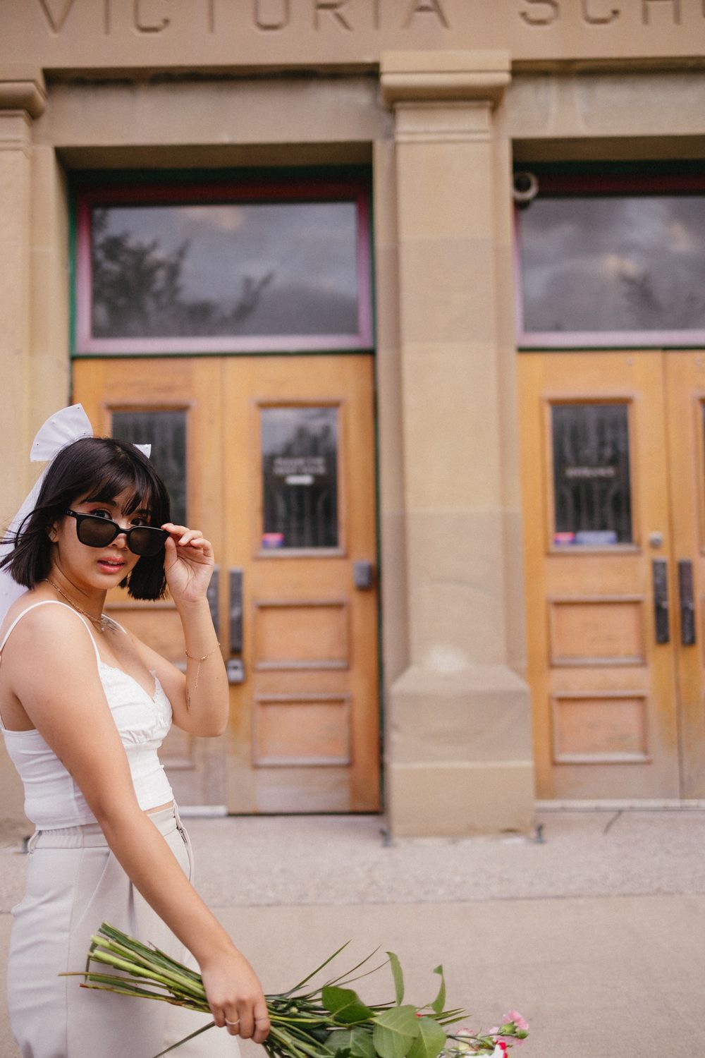 Stylish photo session outside Victoria School featuring sunglasses and a white summer outfit.