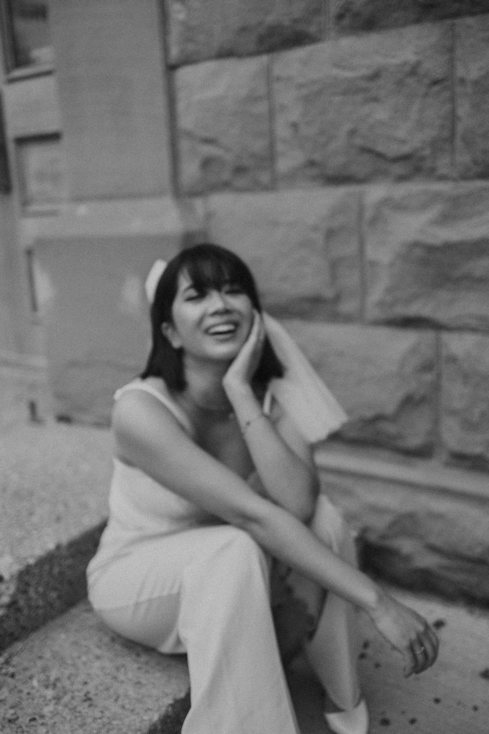 Artistic black and white portraits showing candid laughter against stone walls.