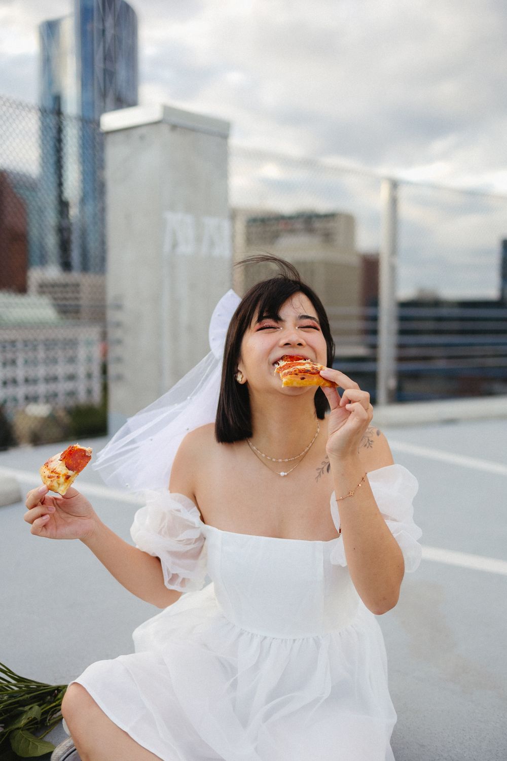 Candid rooftop photoshoot with pizza slices against an urban skyline backdrop.